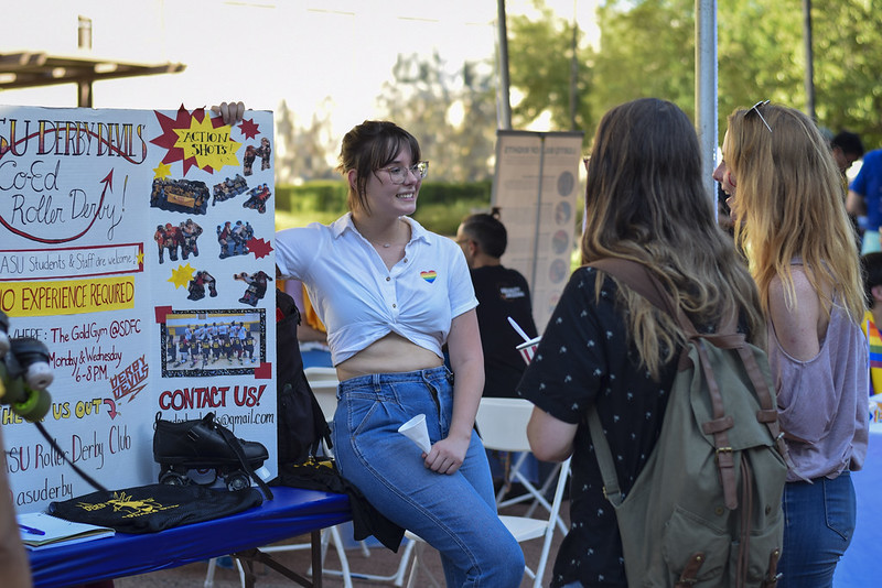 Students talk next to a roller derby poster