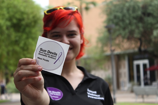 ASU student holding up a sticker for Domestic Violence Awareness Month