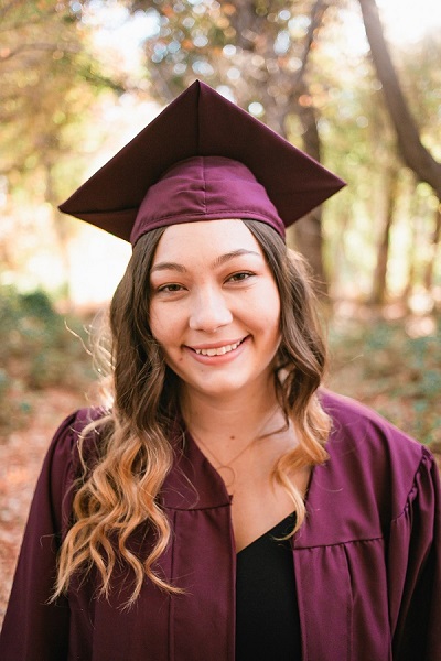 Elizabeth Lund in ASU cap and gown with trees behind her