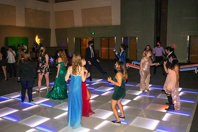 Masked students dancing on a lit up dancefloor