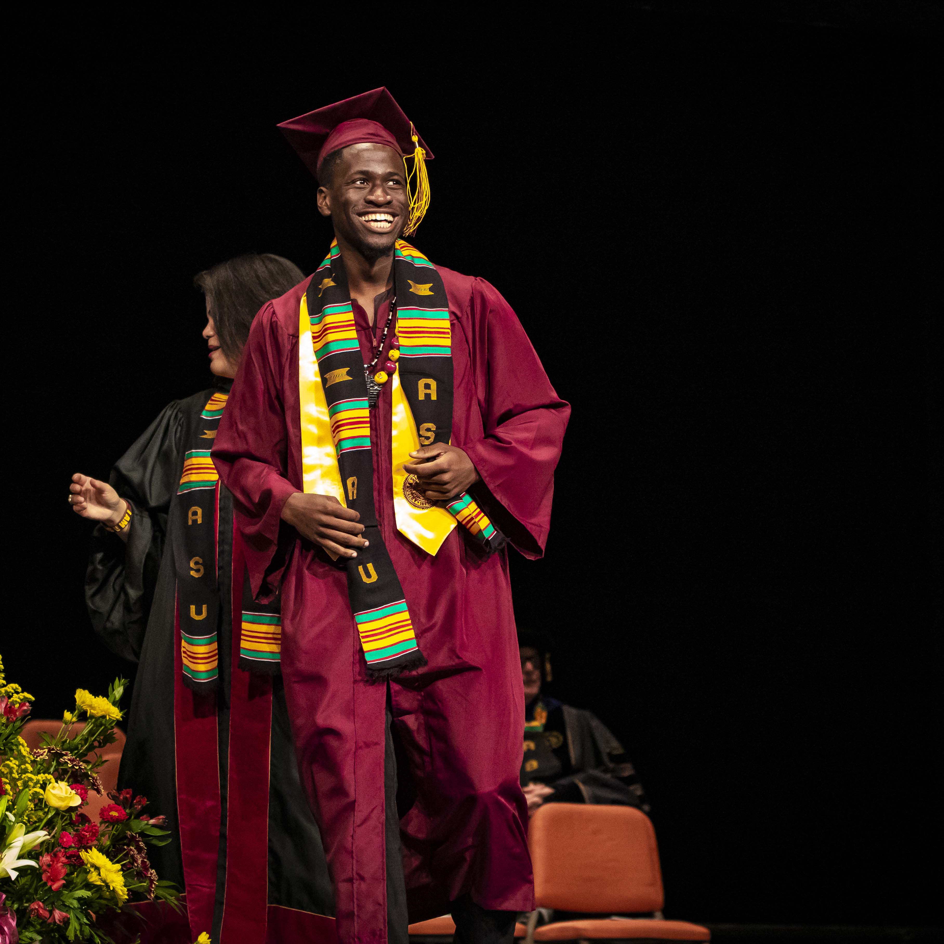 ASU Black African Convocation male graduate onstage with his stole and cap and gown