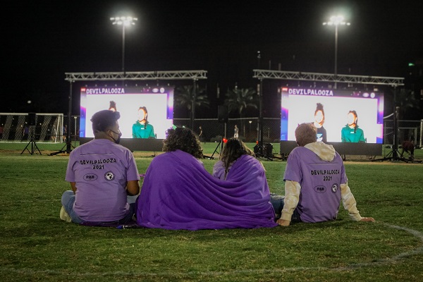 Students on a lawn in front of two large screens at Devilpalooza 2021 at ASU Tempe SDFC Fields