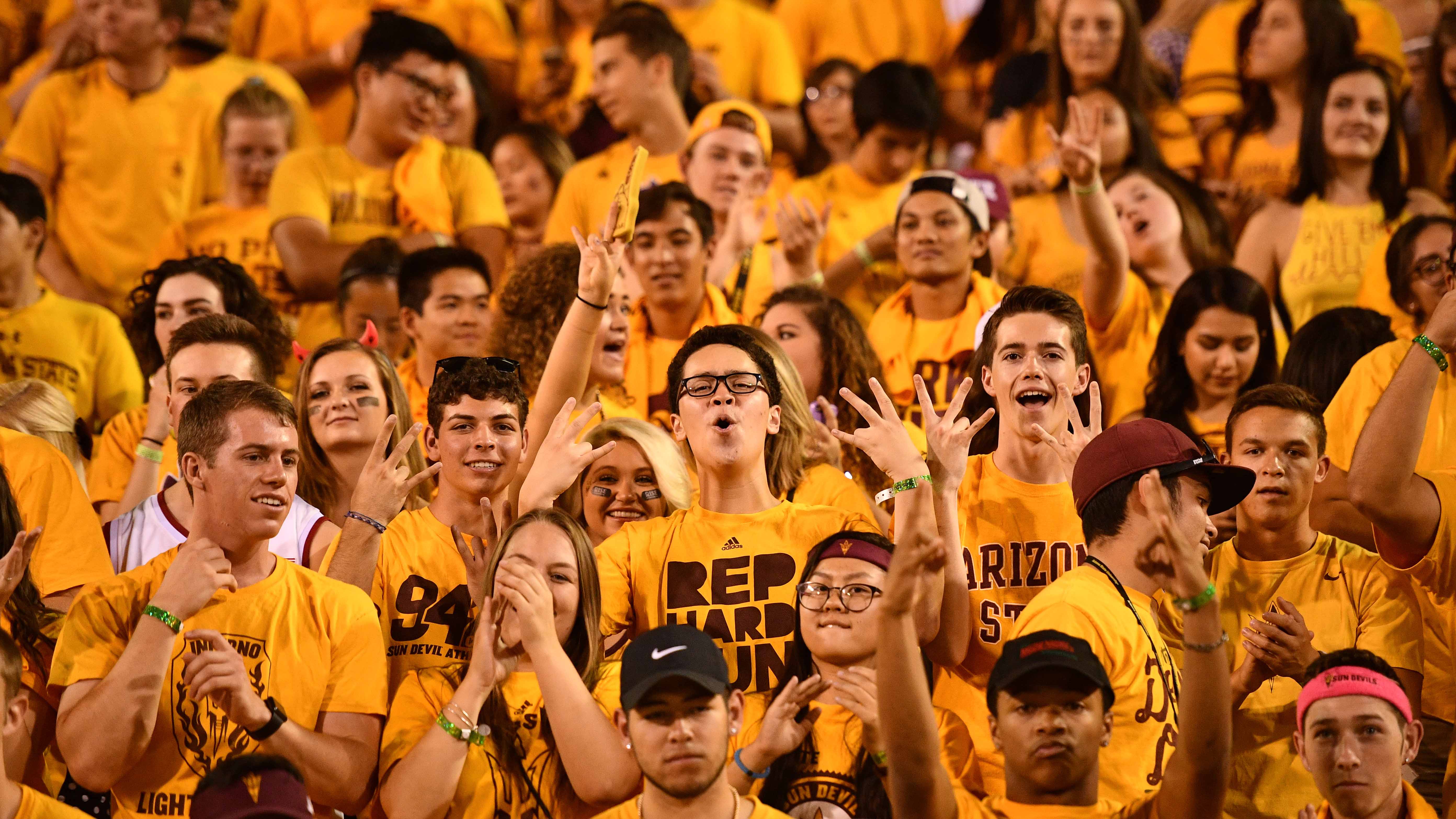 Students wear gold in the Inferno student section at Sun Devil Stadium for a football game