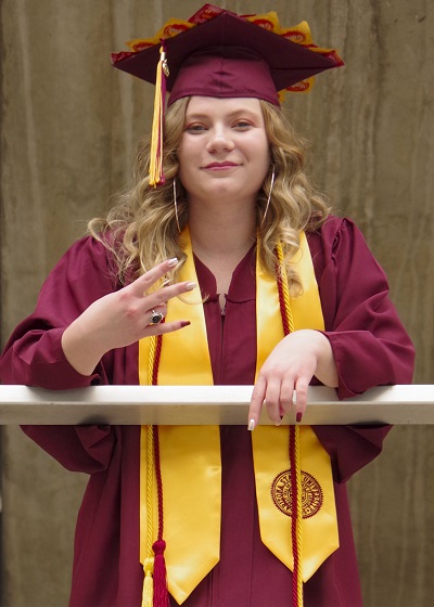 Michelle Coen giving a forks up in her ASU cap and gown