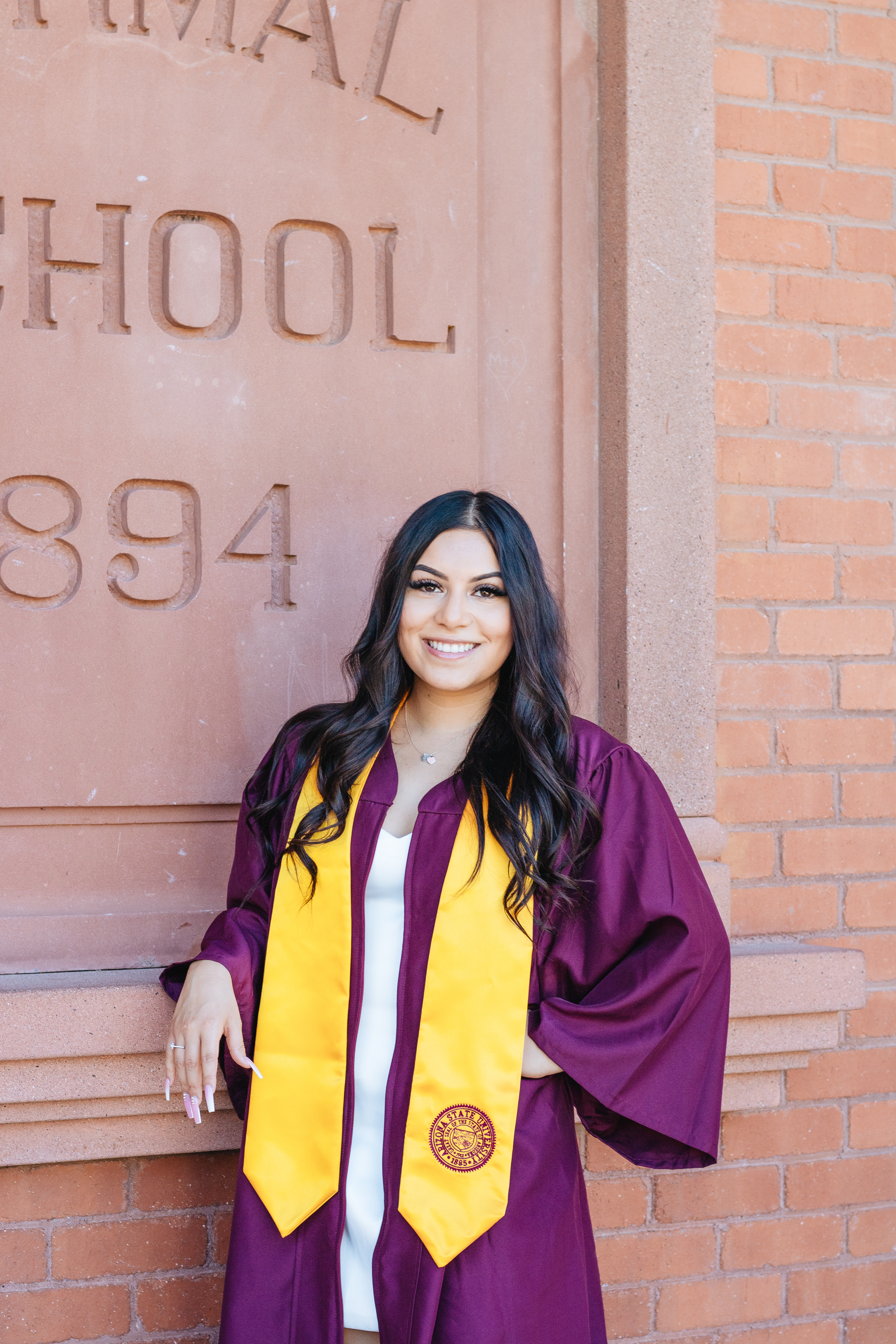  ASU grad Natalie Carranza smiles in her graduation gown in front of Old Main.