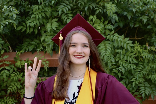  in her cap and gown giving a forks up sign