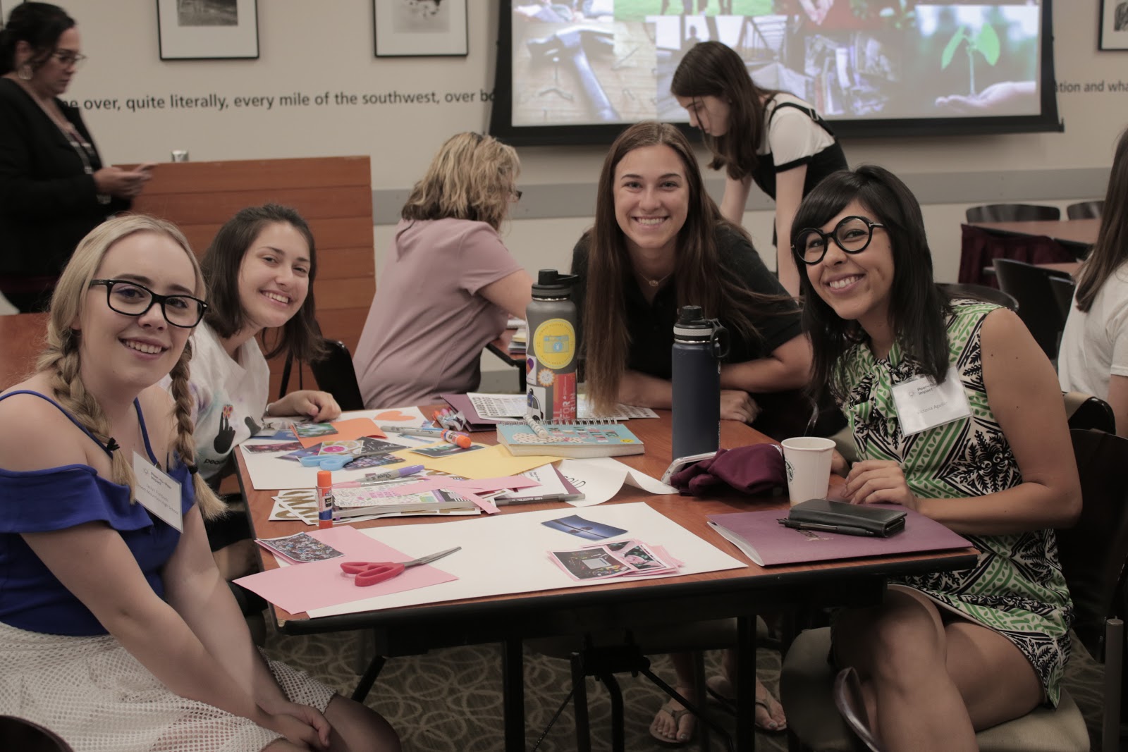 Young women participants at ASU peer to peer symposium smile at a table