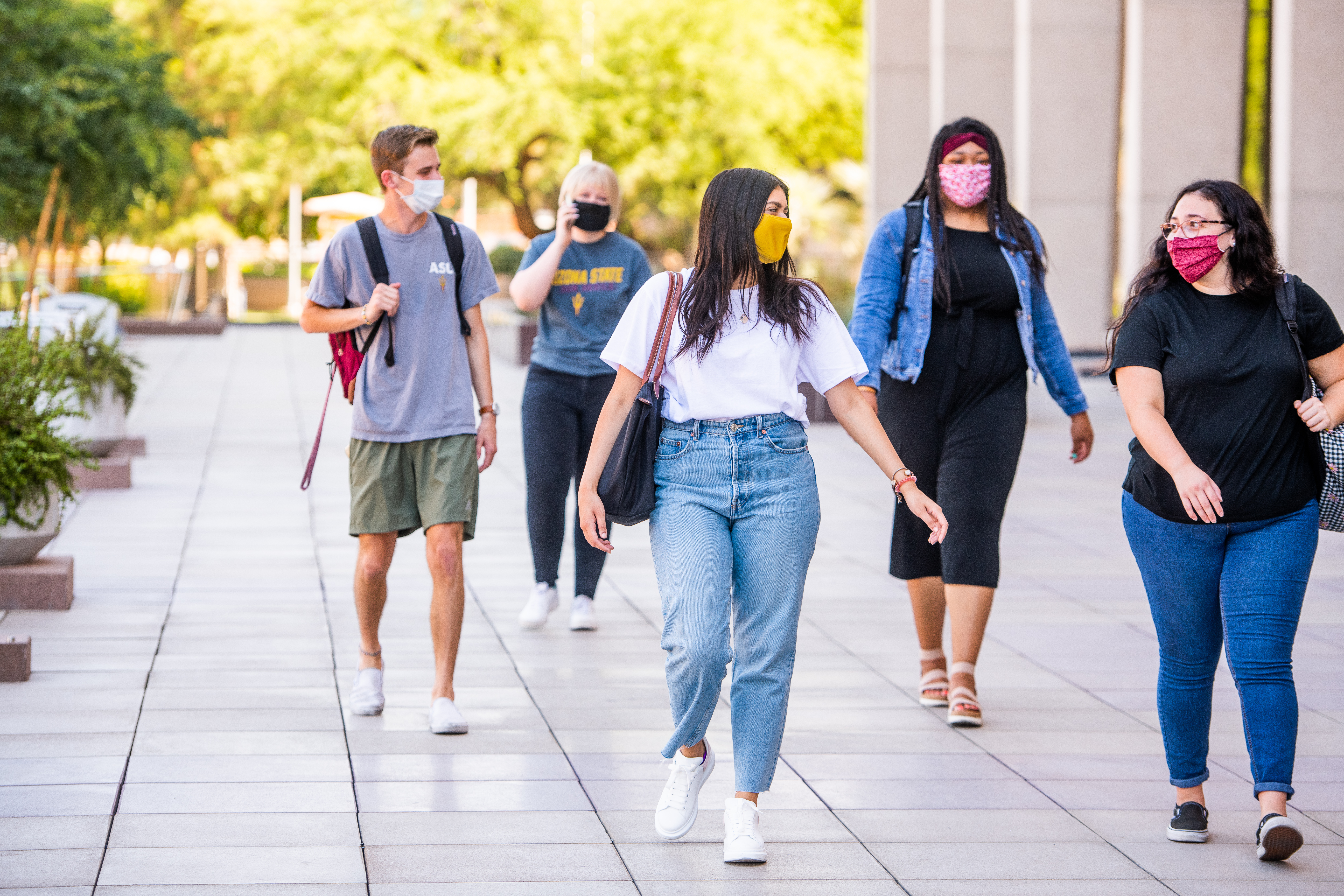Five ASU students wear masks as they walk on campus. 