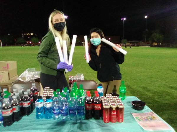 Two ASU students with masks and glow sticks on the SDFC Field