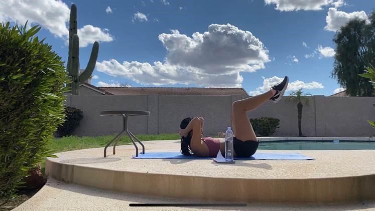 Student doing virtual yoga out by the pool on a sunny day